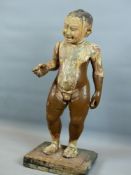 AN UNUSUAL CARVED WOOD ORIENTAL FIGURE OF A NAKED BOY WITH HAPPY SMILING FEATURES. STANDING ON A