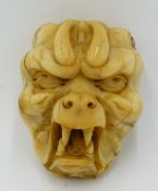 A JAPANESE 19TH. CENTURY CARVED IVORY MASK OF A DEMON OR ONI. 6.5 CM HIGH
