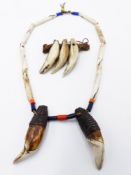 AN ANTIQUE AFRICAN NECKLACE WITH SHELL BEADS AND LIONS TEETH. AND A FURTHER TOOTH PENDANT. (2)