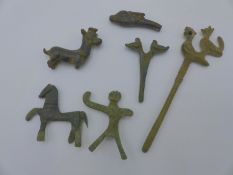 A BRONZE ARCHAIC FORM GARMENT PIN SURMOUNTED WITH BIRDS, A SIMILAR PIN AND FOUR FIGURAL AMULETS, THE