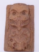 A UNUSUAL TERRACOTTA PANEL DEPICTING IN RELIEF A DEMON SKULL GOD? BREATHING FIRE, 19TH CENTURY OR