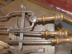 A PAIR OF WROUGHT IRON AND COPPER ARTS AND CRAFTS FIRE DOGS AND A SET OF THREE FIRE TOOLS