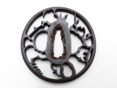 A 17TH CENTURY PIERCED IRON TSUBA DECORATED AFTER STYLIZED BIRDS WITHIN A PLUM TREE