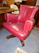 A RED LEATHER UPHOLSTERED SWIVEL ARMCHAIR.