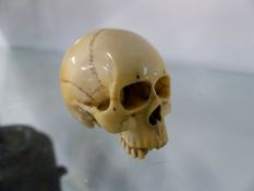 A CARVED IVORY MODEL OF A SKULL. 3.5CM HIGH