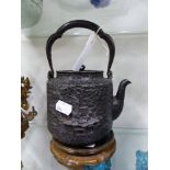 A JAPANESE MEIJI PERIOD IRON TEA KETTLE WITH LANDSCAPE RELIEF DECORATION, THE COPPER LID WITH