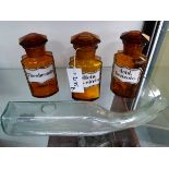 A GROUP OF THREE AMBER GLASS APOTHECARY BOTTLES WITH ENAMEL LABELS TOGETHER WITH A CLEAR GLASS