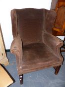 AN ANTIQUE WING BACK ARMCHAIR ON SQUARE LEGS.