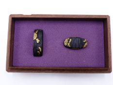 A FINE SET OF SHAKUDO AND GOLD FUCHI AND KASHIRA HIGHLIGHTED IN GOLDS AND DECORATED WITH LILIES ON A