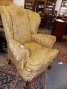 A LARGE GEORGIAN STYLE WING BACK ARMCHAIR ON CARVED CABRIOLE LEGS.