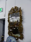 AN ANTIQUE CARVED GILTWOOD FRAMED MIRROR IN THE CHIPPENDALE MANNER. APPROX 130cms HIGH.