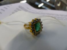A DIAMOND AND EMERALD DRESS RING WITH CENTRE BAGUETTE CUT EMERALD.
