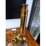 A LARGE LACQUERED BRASS MICROSCOPE BY ROSS, LONDON DISPLAYED UNDER A GLASS DOME.