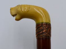 A 19TH CENTURY MALACCA WALKING CANE WITH CARVED IVORY DOG'S HEAD HANDLE AND COPPER REPOUSSE COLLAR.