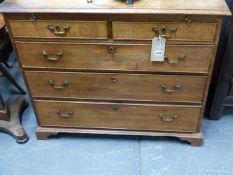 A LATE GEORGIAN OAK CHEST OF TWO SHORT AND THREE LONG GRADUATED DRAWERS WITH BRUSHING SLIDE.