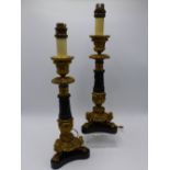 A PAIR OF GILT AND PATINATED BRONZE ANTIQUE FRENCH EMPIRE STYLE CANDLESTICKS NOW MOUNTED AS LAMPS.