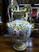 A LARGE CONTINENTAL MAJOLICA TWIN HANDLE URN WITH CENTRAL CARTOUCHE SURROUNDED BY FLORAL SPRAYS.