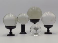 A GROUP OF FIVE ANTIQUE ROCK CRYSTAL BALLS SOME WITH ASSOCIATED STANDS.