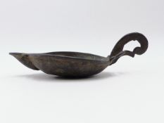 AN EARLY BRONZE OIL LAMP WITH LIPPED OPEN PAN WITH FLAT SCROLL FORM HANDLE. 16CMS. OVERALL