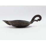 AN EARLY BRONZE OIL LAMP WITH LIPPED OPEN PAN WITH FLAT SCROLL FORM HANDLE. 16CMS. OVERALL