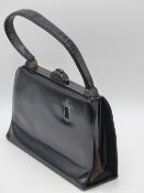 A RARE AMERICAN VINTAGE BLACK HANDBAG WITH BATTERY POWERED VANITY WITHIN.