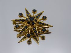 A 9CT YELLOW GOLD SIX POINTED STELLATE FRAME BROOCH ORNAMETED WITH A FLOWER SHAPED SETTING TO THE