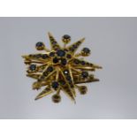 A 9CT YELLOW GOLD SIX POINTED STELLATE FRAME BROOCH ORNAMETED WITH A FLOWER SHAPED SETTING TO THE