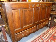 AN 18TH.C.OAK COFFER WITH FIVE PANEL FRONT OVER TWO DRAWERS, BRASS STUDDED DATE 1772. 127CMS WIDE.