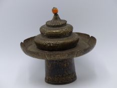 A TIBETAN WHITE METAL FOOTED DOME COVERED CEREMONIAL STAND WITH OVERALL CHASED AND REPOUSSE