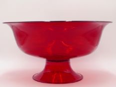 A LARGE RUBY GLASS FOOTED CENTRE BOWL WITH SWIRLED BLOWN DECORATION. 34CMS DIAMETER.