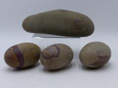 A GROUP OF FOUR INDIAN SHIVA LINGAM STONE EACH OF NATURAL GREY STONE WITH RED INCLUSIONS. LARGEST