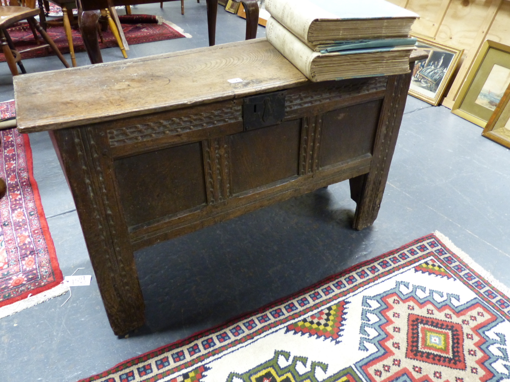 AN EARLY CARVED OAK COFFER WITH THREE PANEL FRONT, UNUSUALLY HIGH STILE FEET WITH PLANK CUT OUT