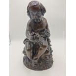 AN ANTIQUE CARVED WOOD FIGURE OF A SEATED CHILD HOLDING FLOWERS. 37CMS HIGH.