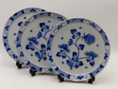 THREE ANTIQUE BLUE AND WHITE DELFT PLATES EACH DECORATED WITH A FLORAL SPRAY. 22.5CMS DIAMETER (3)