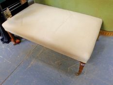 A LARGE STOOL ON TURNED LEGS WITH BRASS CASTERS. 104X65CMS.