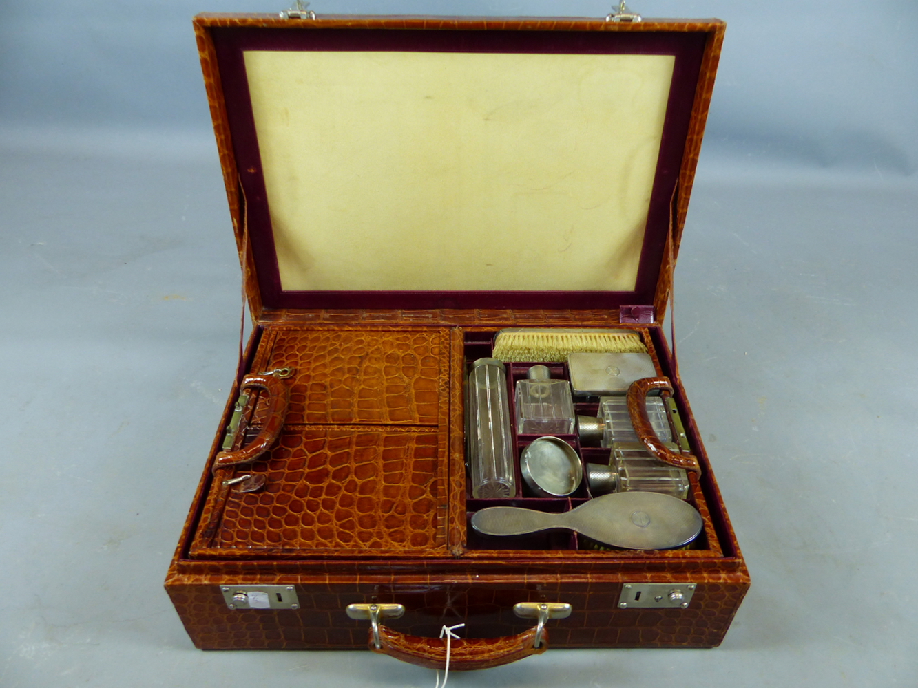 AN EARLY 20TH CENTURY CROCODILE LEATHER TRAVELLING VANITY CASE. PART FITTED WITH VARIOUS WHITE METAL