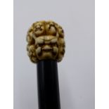 A 19TH CENTURY JAPANESE CARVED IVORY WALKING CANE TOP CARVED WITH MULTIPLE DEITIES FACES AND ONI,
