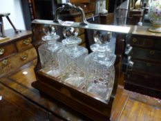 AN EDWARDIAN INLAID MAHOGANY THREE BOTTLE TANTALUS WITH SILVERED BRASS FITTINGS.