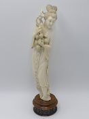 AN EARLY 20TH.C.CHINESE CARVED IVORY STANDING FIGURE OF A MAIDEN HOLDING FRUIT ON A PIERCED HARDWOOD