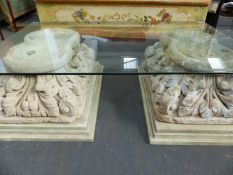 A CONTEMPORARY GLASS TOP COFFEE TABLE, THE BASES CONSTRUCTED WITH CARVED LIMESTONE CAPITALS.