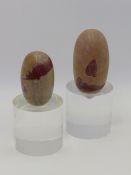 TWO INDIAN SHIVA LINGAM STONES OF BROWNISH GREY COLOUR WITH RED INCLUSION, LARGEST 11CM BOTH NOW