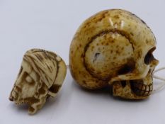 A LARGE 19TH. CENTURY CARVED BONE MOMENTO MORI SKULL TOGETHER WITH ANOTHER SMALLER EXAMPLE. 5CMS.