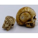 A LARGE 19TH. CENTURY CARVED BONE MOMENTO MORI SKULL TOGETHER WITH ANOTHER SMALLER EXAMPLE. 5CMS.