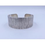 A GUILD OF HANDICRAFT SILVER CUFF BANGLE WITH BARK EFFECT FINISH. HALLMARKED LONDON 2005. TOTAL
