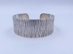 A GUILD OF HANDICRAFT SILVER CUFF BANGLE WITH BARK EFFECT FINISH. HALLMARKED LONDON 2005. TOTAL