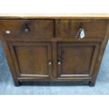 AN ANTIQUE OAK COUNTRY MADE SIDE CABINET WITH TWO DRAWERS OVER TWO PANEL DOOR CUPBOARD SECTION. H.