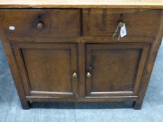 AN ANTIQUE OAK COUNTRY MADE SIDE CABINET WITH TWO DRAWERS OVER TWO PANEL DOOR CUPBOARD SECTION. H.