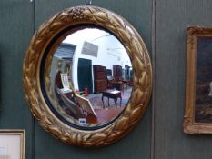 A WM.IV.CARVED GILTWOOD CONVEX MIRROR WITH TIED LEAF FORM MOULDED FRAME AND EBONISED SLIP. DIA.