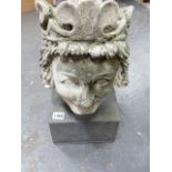 AN ANTIQUE WEATHERED AND CARVED HEAD OF A ROYAL FIGURE WEARING A CROWN, ON A LATER STONE PLINTH.