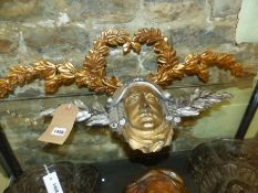 AN ANTIQUE SILVERED AND GILT CARVED APPLIQUE OF A CLASSICAL MASK WITH LAUREL LEAVES TOGETHER WITH
